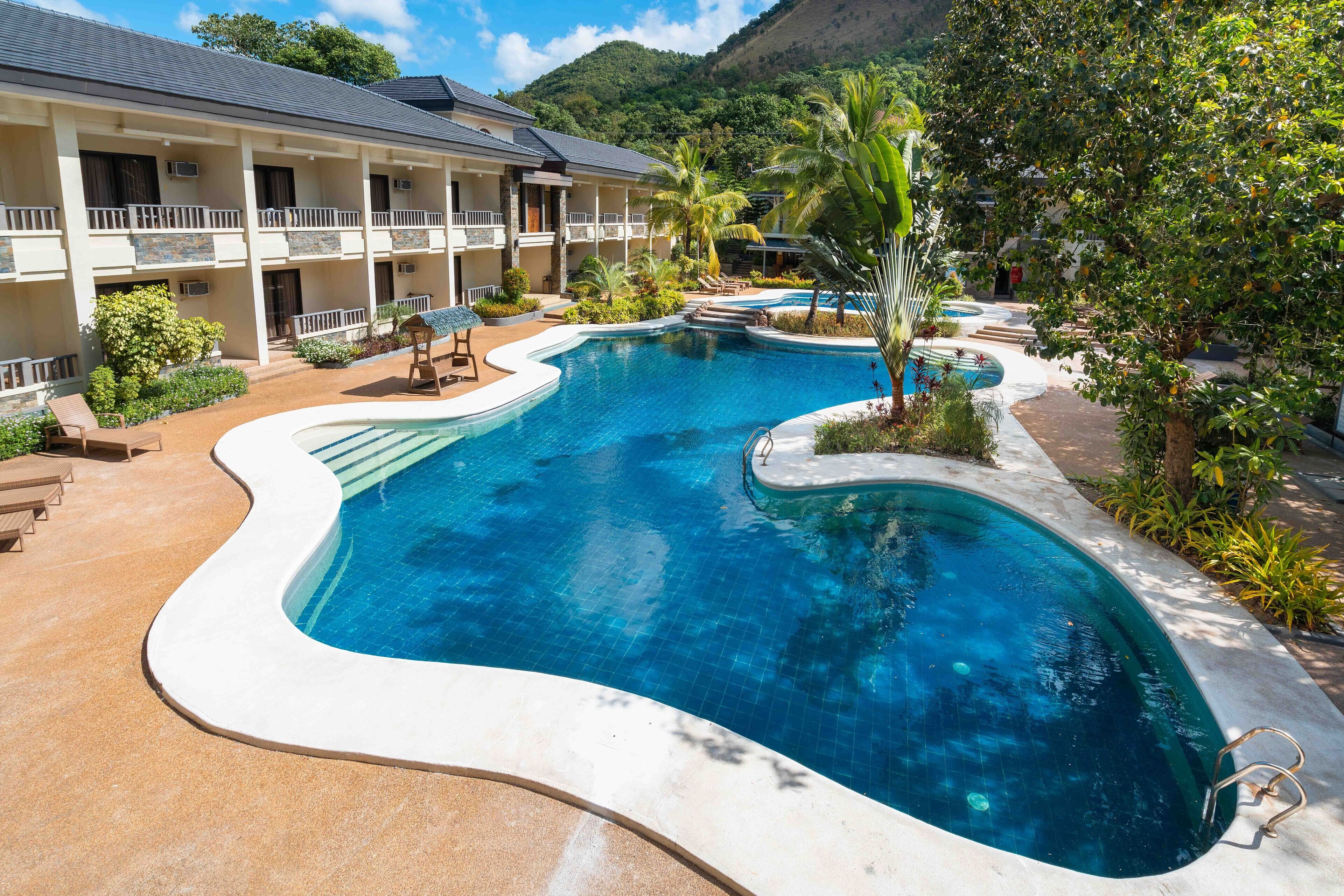 Een buitenzwembad, parasols bij het zwembad en ligstoelen