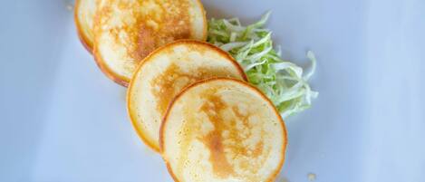 Un plato con tres tortitas y lechuga rallada.