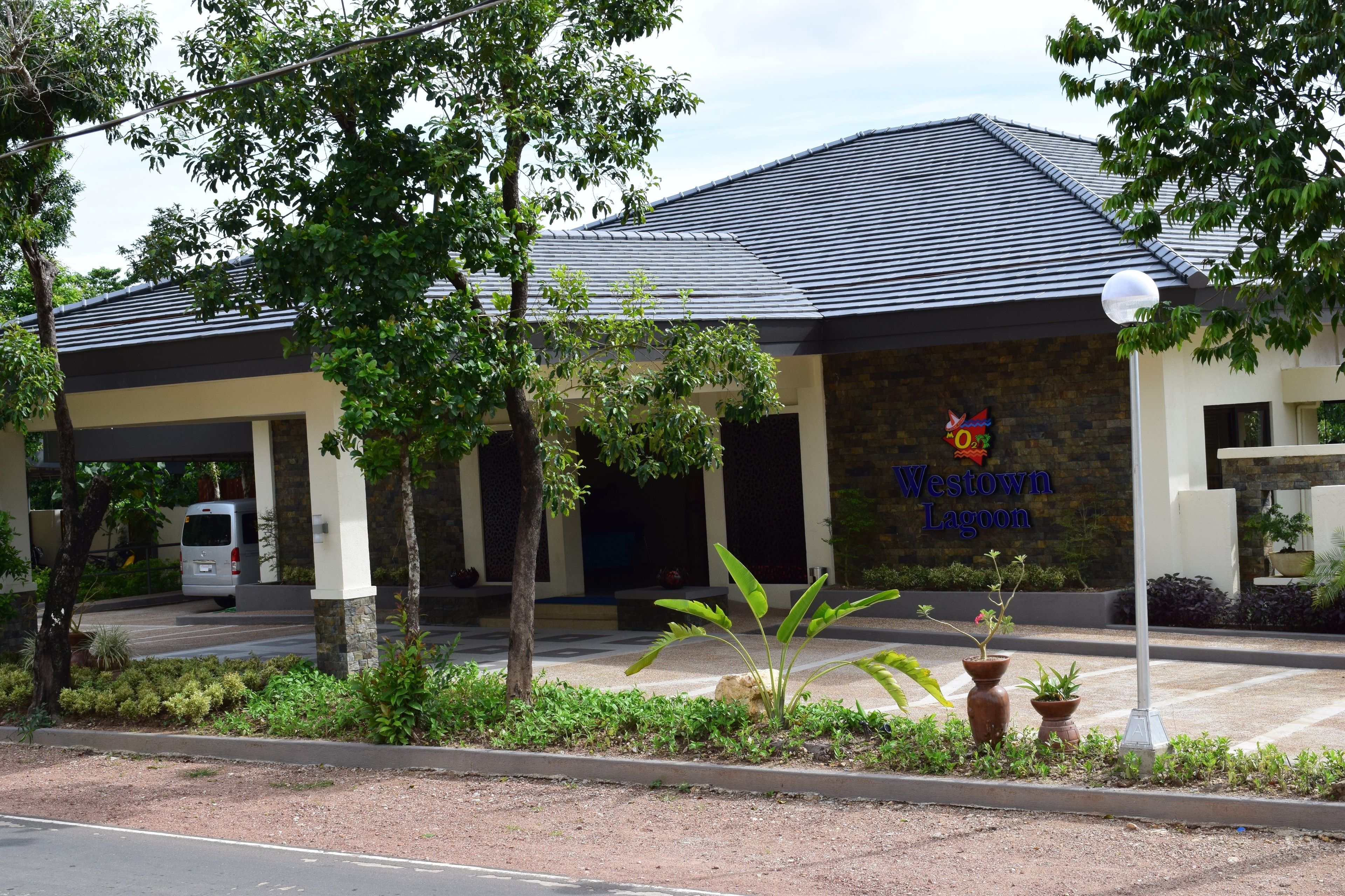 A Westown Lagoon building with a covered entrance, potted plants, and a parked van.