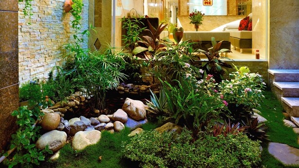 A hotel lobby with a stone wall, indoor plants, a reception desk, and a sign with the hotel's name. - You And Me Hotel (Ho Chi Minh City)