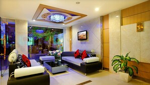 A modern lobby with a seating area, a chandelier, and a television screen. - You And Me Hotel (Ho Chi Minh City)