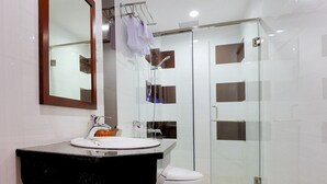 A modern bathroom with a glass-enclosed shower, a white toilet, and a black vanity with a mirror. - You And Me Hotel (Ho Chi Minh City)