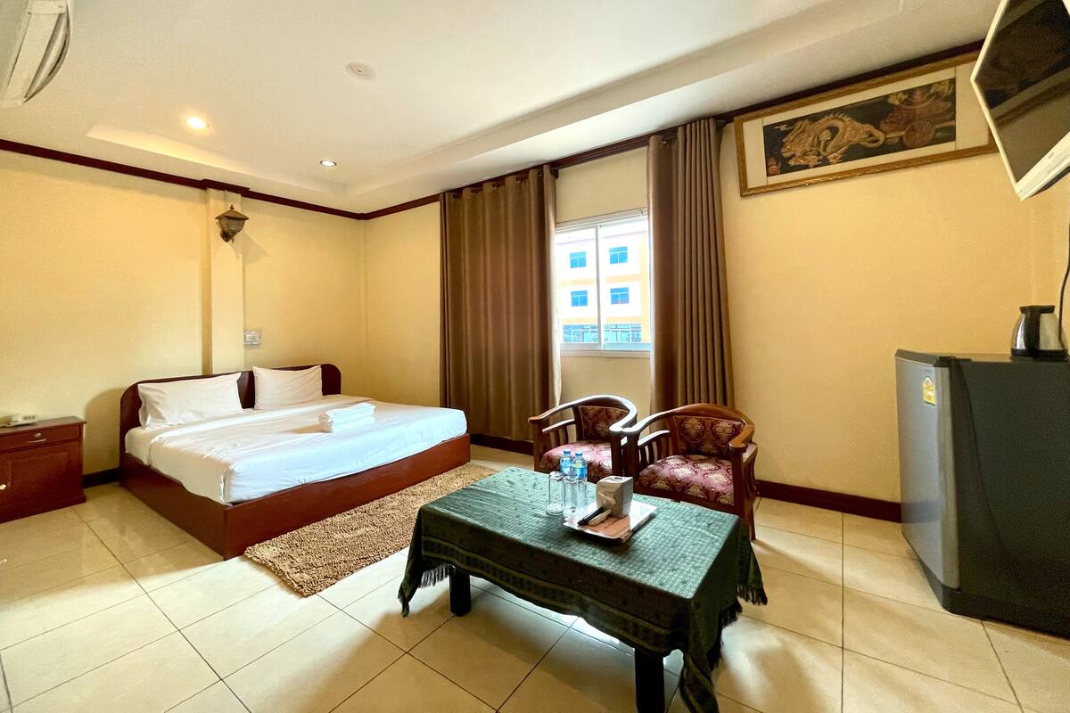 Una habitación de hotel con cama, una mesa con manta, una silla, un escritorio y televisión.