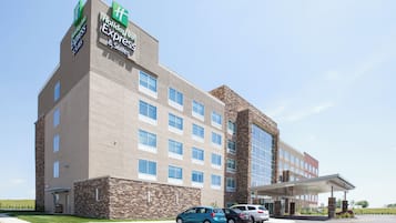 A Holiday Inn Express hotel with a brick facade, multiple windows, and a parking lot with cars.