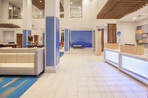 A hotel lobby with a reception desk, seating area, and a staircase.