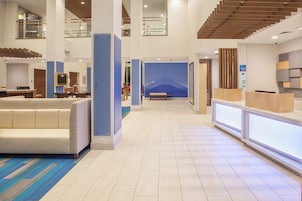 A hotel lobby with a reception desk, seating area, and a staircase.