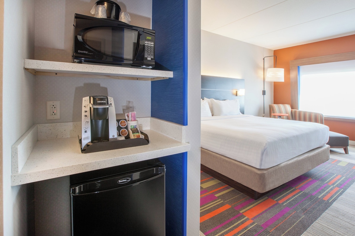 Ein Hotelzimmer mit Bett, einer Mikrowelle, einer Kaffeemaschine und einem kleinen Kühlschrank.
