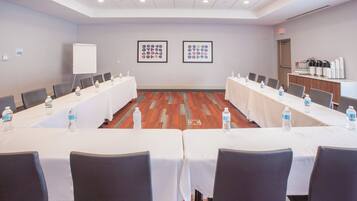 A conference room with a long table, chairs, water bottles, and a whiteboard.