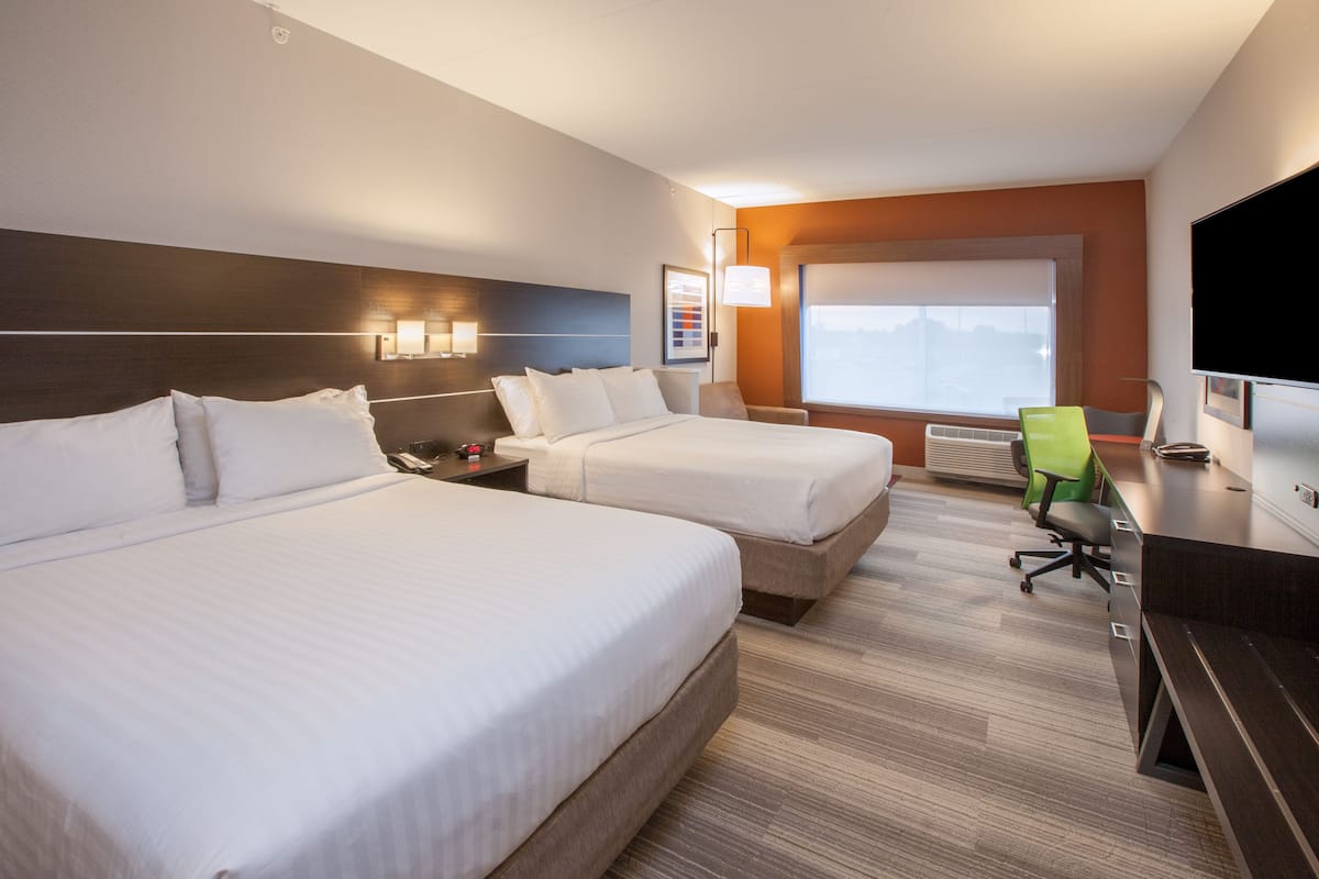 Ein Hotelzimmer mit zwei Betten, einem Schreibtisch, einem Stuhl, einem Fernseher und einem Fenster mit Blick.