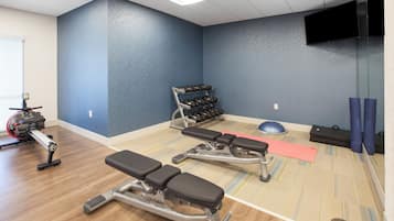 A gym with exercise equipment, a blue wall, and a television.