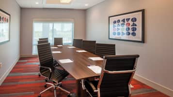 A conference room with a long table, six chairs, and a framed abstract art piece on the wall.