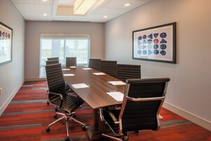 A conference room with a long table, six chairs, and a framed abstract art piece on the wall.