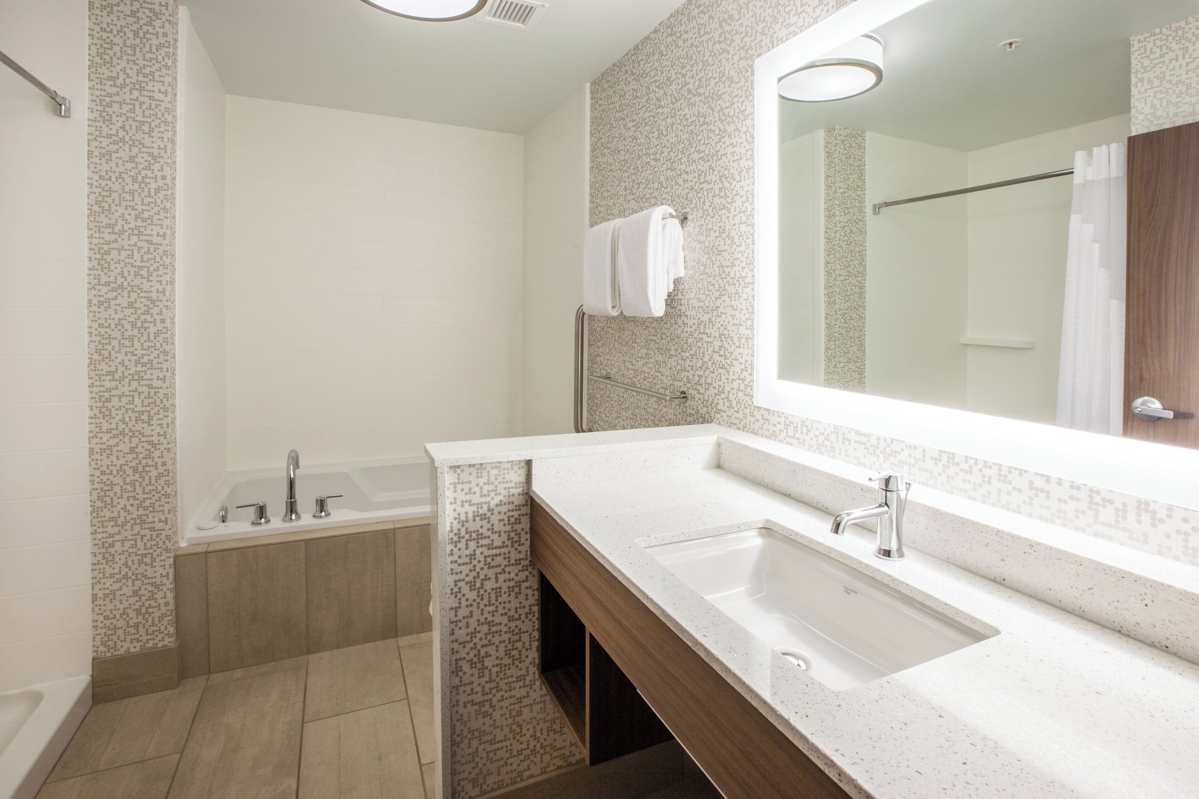 Une salle de bain moderne avec une baignoire, un lavabo et un grand miroir.