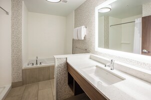 A modern bathroom with a bathtub, a sink, and a large mirror.