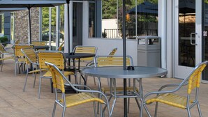 An outdoor patio area with tables and chairs, umbrellas, and a stone wall. - Fairfield Inn & Suites by Marriott Richmond Ashland (Ashland)
