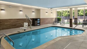 A swimming pool with a tiled deck, a lounge area with chairs and a table, and a view of greenery outside. - Fairfield Inn & Suites by Marriott Richmond Ashland (Ashland)