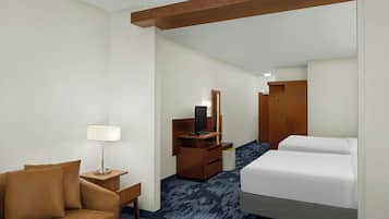 A hotel room with a bed, a desk with a lamp, a TV, and a wardrobe.