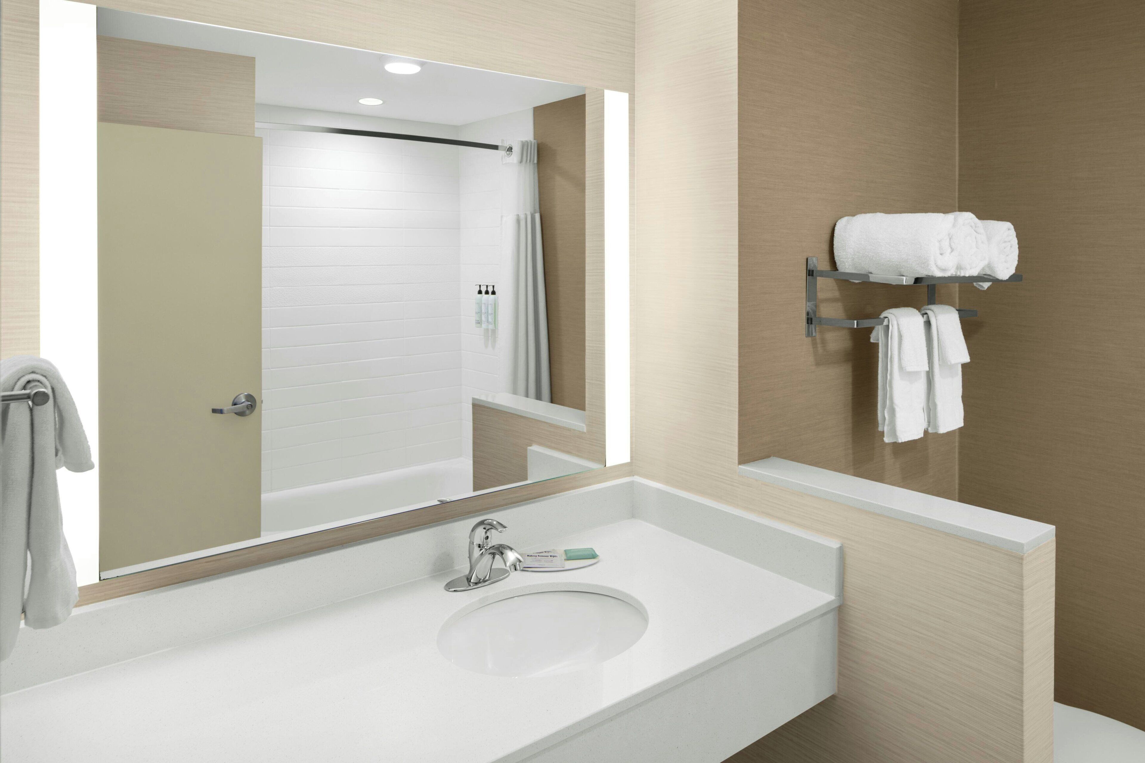 A bathroom with a white sink, a mirror, and a towel rack with towels.