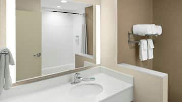 A bathroom with a white sink, a mirror, and a towel rack with towels.