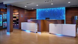 A reception area with a wooden reception desk, a blue decorative wall, and a vending machine with snacks. - Fairfield Inn & Suites by Marriott Alexandria (Alexandria)