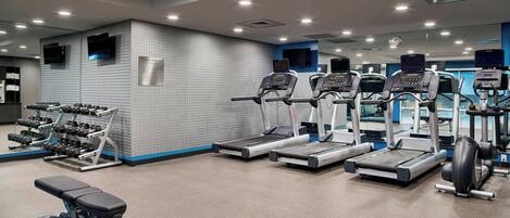A gym with treadmills, dumbbells, and weight machines.