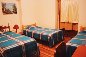 A room with two beds, a wooden headboard, a red lamp, and a painting on the wall. - Quito Backpacker Guest House (Quito)