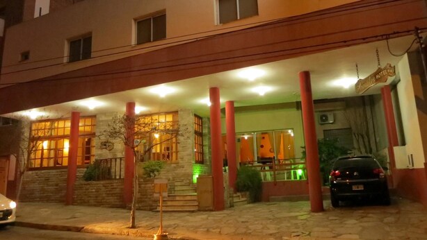 A hotel with a stone facade, red pillars, and a sign indicating it is a hotel. - Hotel Arenales (Villa Carlos Paz)