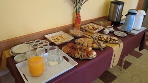A breakfast buffet with various food items, including pastries, fruits, and beverages. - Hotel Arenales (Villa Carlos Paz)