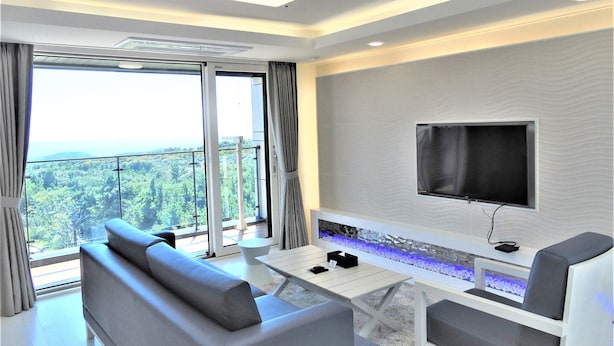 Un salon moderne avec un canapé, une table basse et un téléviseur à écran plat fixé au mur.