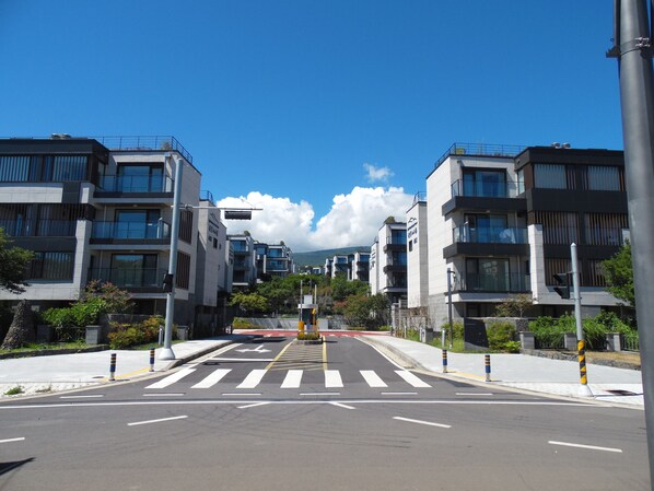 Una calle urbana moderna con edificios contemporáneos, un paso de peatones y un cielo azul despejado.