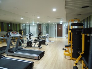Un gimnasio con cintas de correr, elípticas y equipo de levantamiento de pesas.