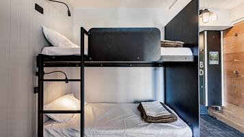 A bunk bed room with a wooden door, a light switch, and a wall-mounted light fixture.