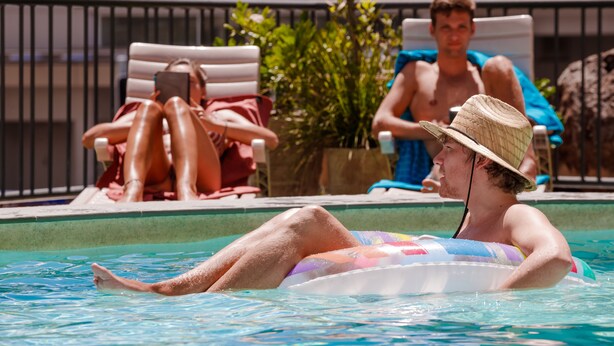 Zona de piscina con sillones de descanso y una persona en el agua.