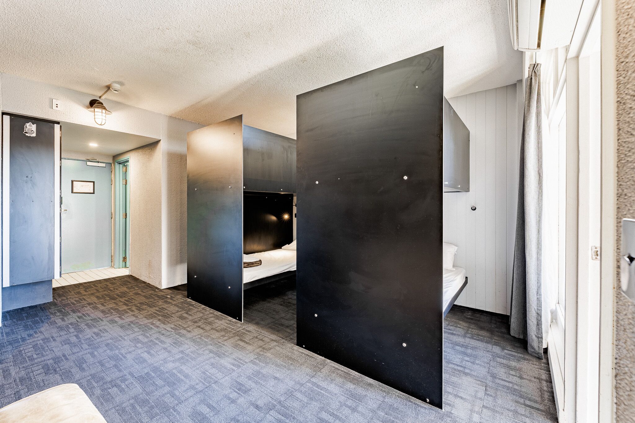 Quarto de hotel moderno com uma cama grande, banheiro separado e uma pequena área de estar.