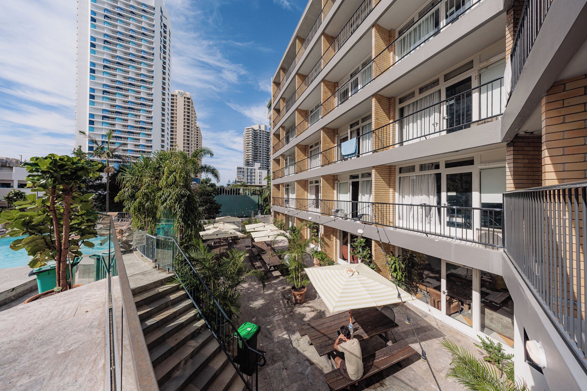 A hotel with outdoor seating, a pool, and a view of tall buildings.