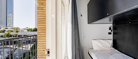 Una habitación de hotel moderna con balcón, cama y vista a la ciudad.
