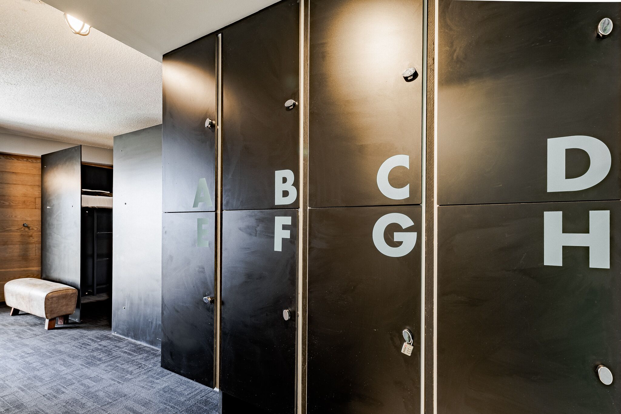 A modern hotel lobby with a seating area and a row of lockers labeled with letters.