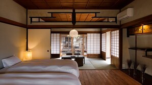 Habitació tradicional japonesa amb tatami, sostre de fusta baix i portes corredisses shoji.