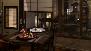 Una sala de menjador japonesa tradicional amb esteves de tatami, una taula baixa i una porta corredissa que dona a un jardí.