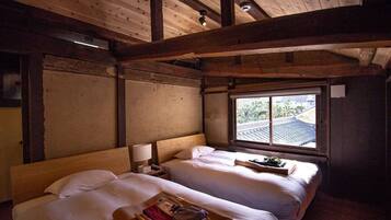 Una habitación con dos camas, vigas de madera, un ventanal con vistas y una mesita de noche con lámpara.