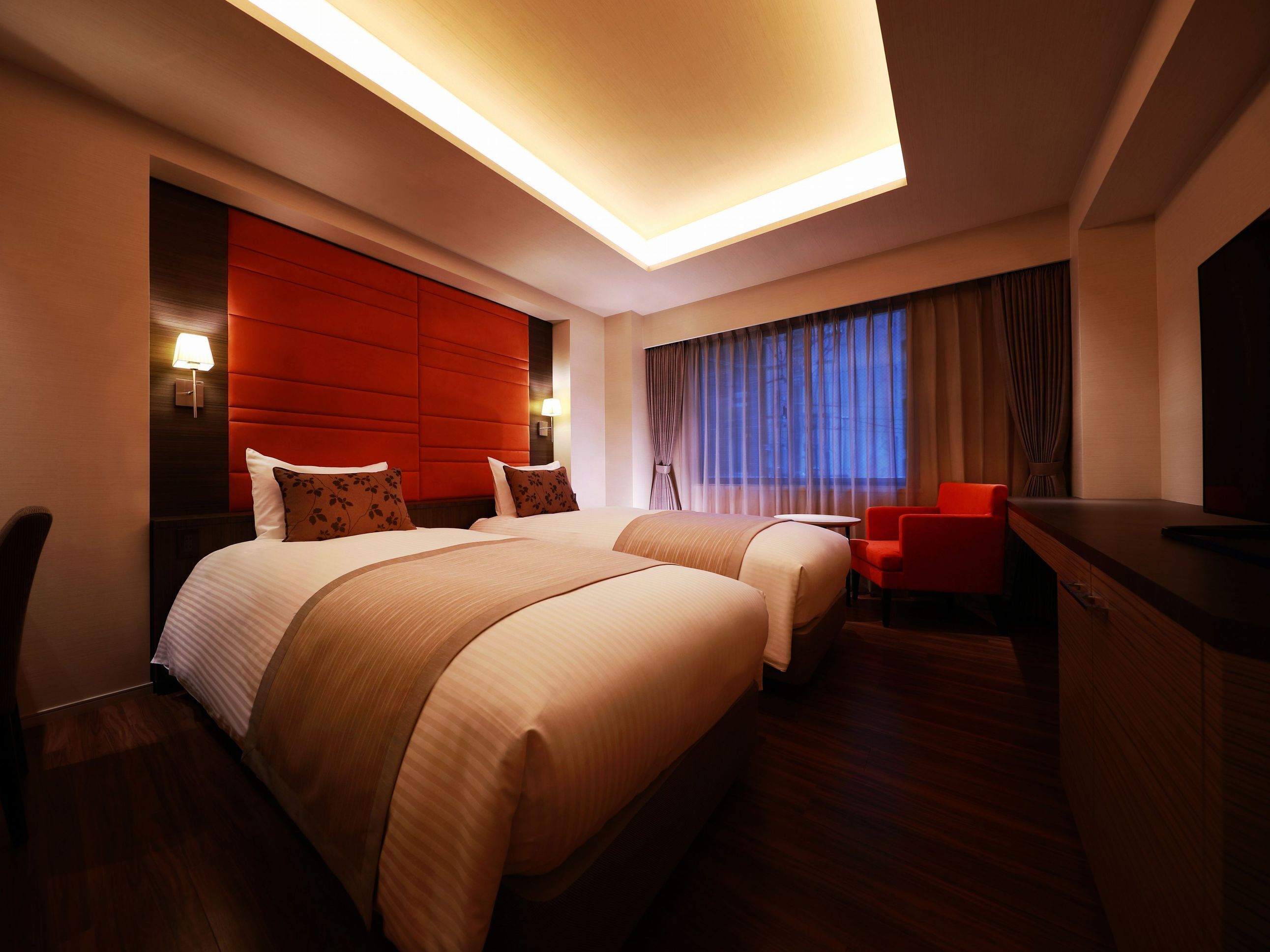 A hotel room with a large bed, a desk, and a chair.