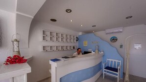 Un comptoir d’accueil agrémenté d’une touche de bleu, un banc blanc et une étagère fixée au mur avec une pancarte indiquant « BIENVENUE ».