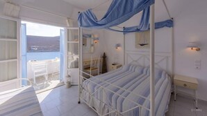 Une chambre à coucher avec un lit, une table de chevet et une vue sur la mer.
