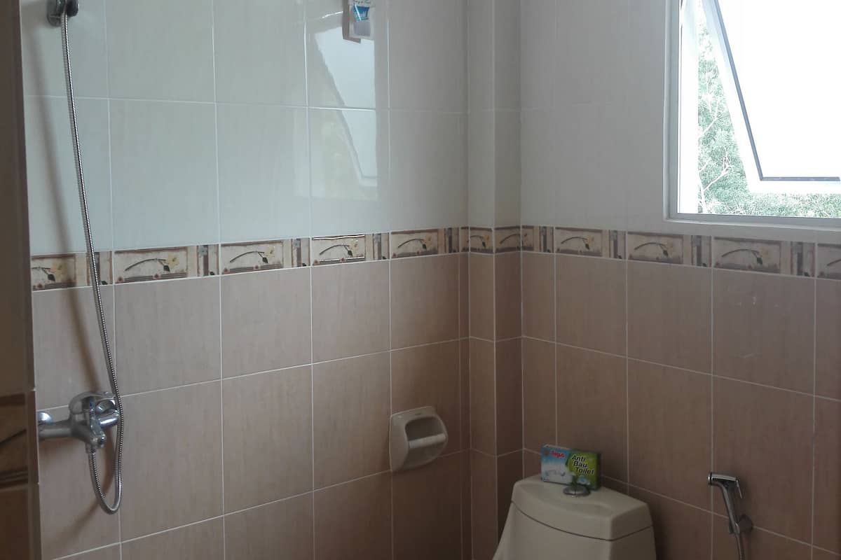 A bathroom with a toilet, a shower, and a window.