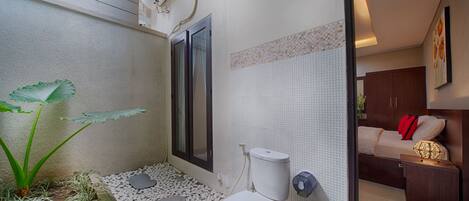 Un baño pequeño con inodoro, zona de ducha y una jardinera con plantas.