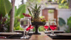 Een gedekte tafel met een ananas als middelpunt, wijnglazen en een tropische setting.