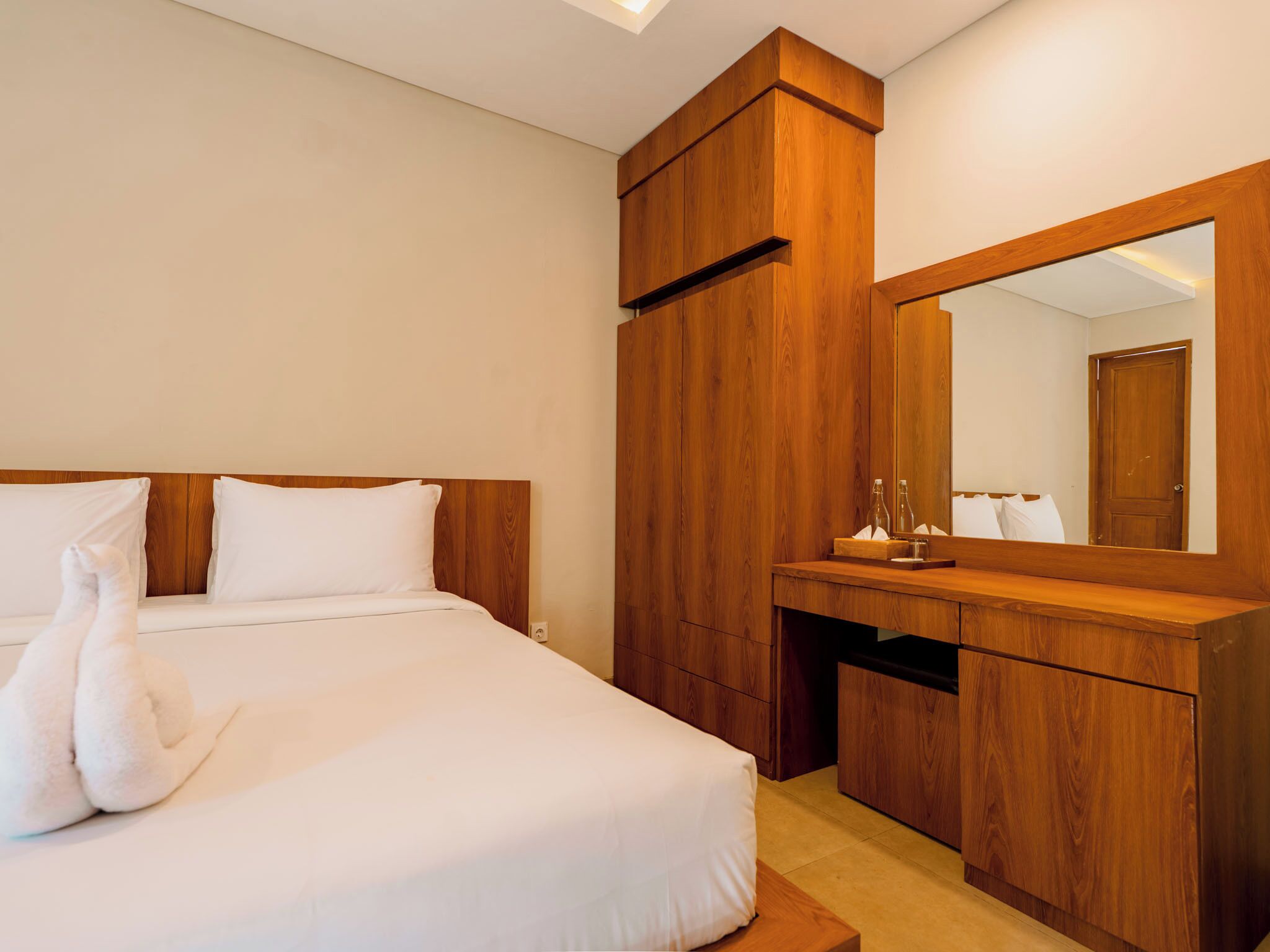 Una camera d'albergo con un letto, un armadio in legno e uno specchio.