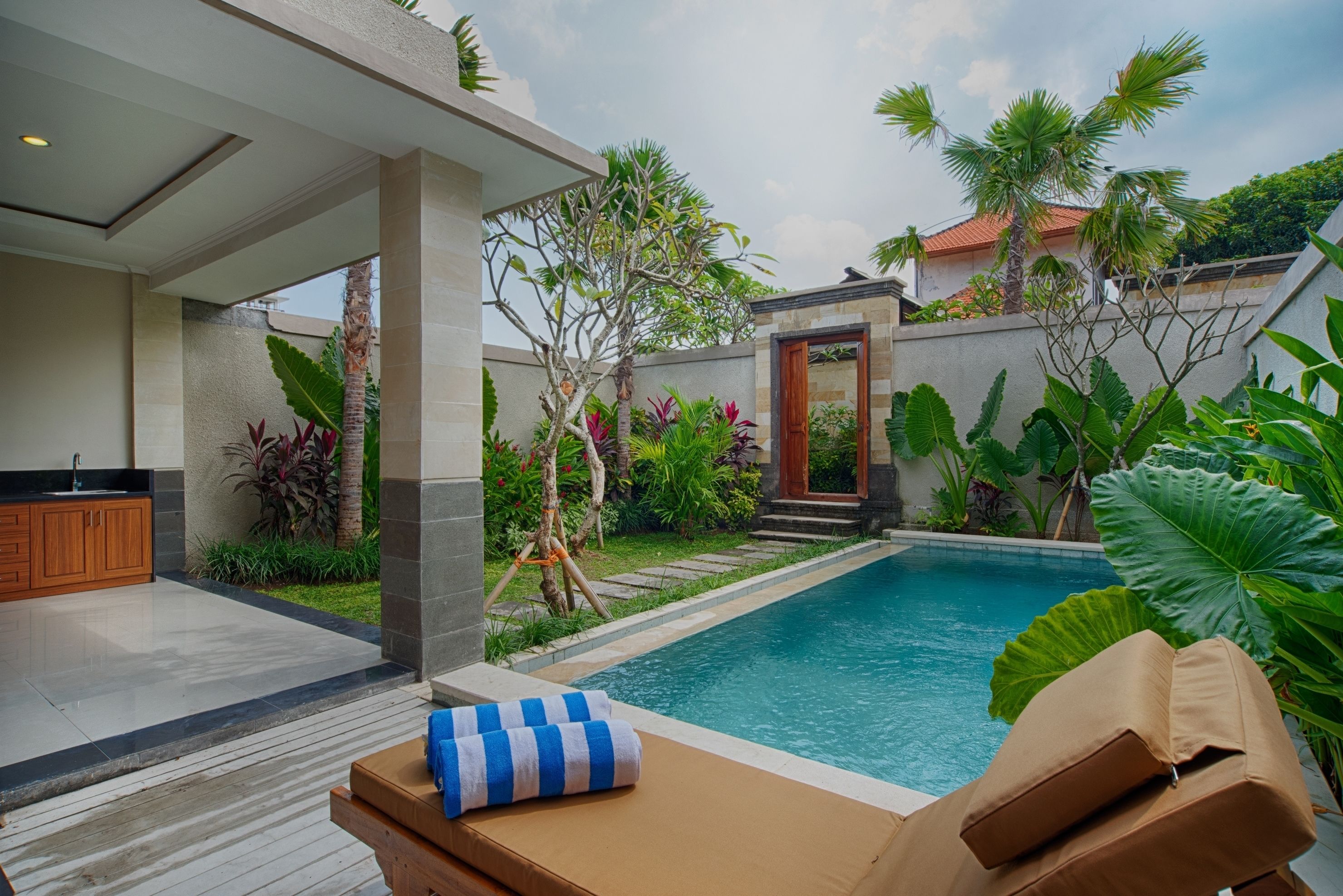 A modern outdoor pool area with a lounge chair and a wooden cabinet.
