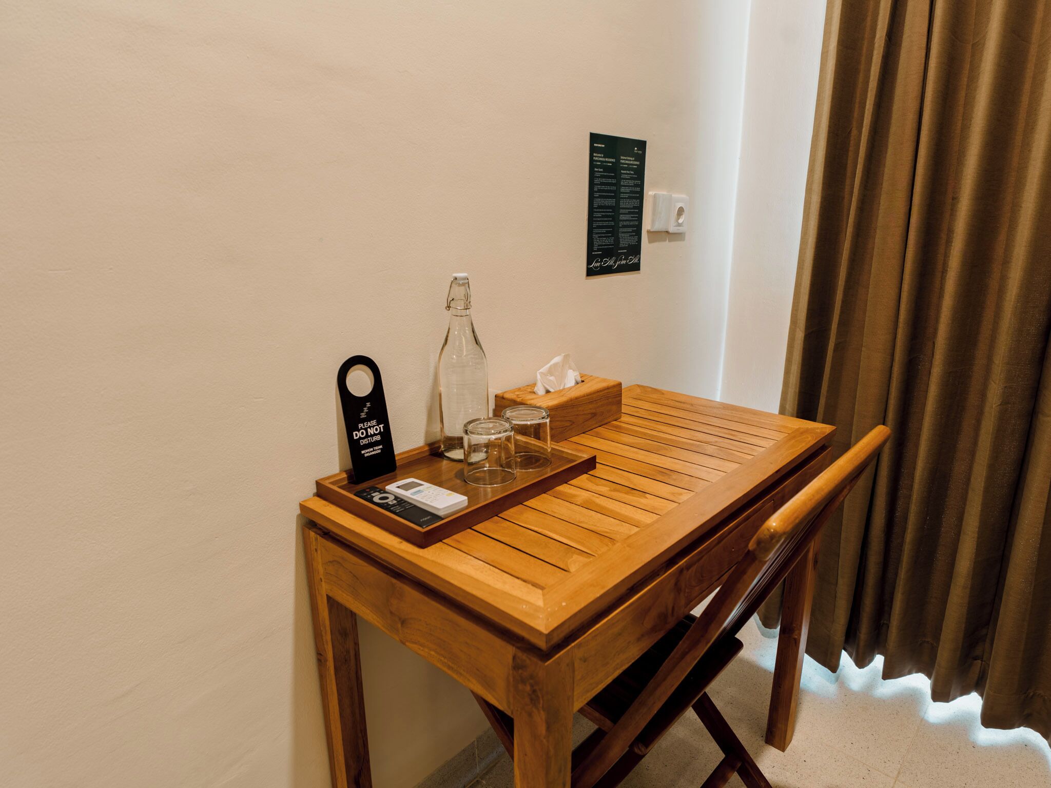 Een houten tafel met een dienblad, een fles, een zakdoosje en een bord.