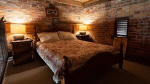 A bedroom with a wooden bed, two bedside tables, a brick wall, and a wooden ceiling. - GRAMPIANS HISTORIC TOBACCO KILN (Moutajup)